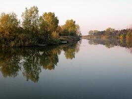 autunno colorato alberi riflettendo nel tranquillo fiume foto