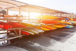 nel luce del sole, rosso, giallo e bianca kayak posto sottosopra giù su metallo Conservazione cremagliere. rifornito canoa nel il petto, Francia 28 Maggio 2018 foto