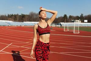 bellissimo caucasico ragazza atleta riposo dopo jogging su un' in esecuzione traccia. foto