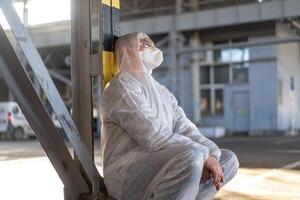 disperazione assistenza sanitaria lavoratore nel bianca covid protettivo tuta da lavoro. stanco maschio caucasico medico nel depressione durante coronavirus pandemia foto