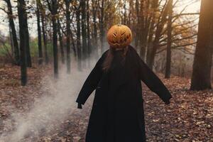 un' terribile creatura nel il autunno foresta nel il sera. contento Halloween. zucca testa. uomo con un' zucca su il suo testa e un' nero mantello foto