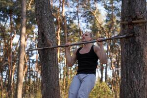 bello caucasico uomini pull-up all'aperto allenarsi attraversare formazione mattina pompaggio su braccio esercizio gli sport terra natura foresta foto