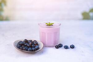 gustoso fresco mirtillo Yogurt shake dolce nel bicchiere in piedi su bianca tavolo sfondo. foto