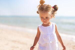 poco caucasico ragazza 3 anni vecchio passeggiate lungo il mare costa. carino bambino ritratto su il spiaggia. famiglia vacanza foto