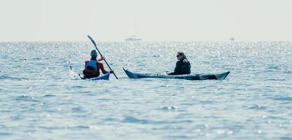 uomo donna mare kayak. contento gratuito uomo e donna nel kayak su oceano, paddling con di legno remo. calma mare acqua e orizzonte nel sfondo. attivo stile di vita a mare. estate vacanza. foto