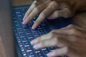 vicino su Immagine di mani digitando su il computer portatile computer tastiera e fare surf il Internet a casa. libero professionista copywriter Lavorando progetto, digitando testo, modificare qualche cosa. a distanza lavoro concetto foto