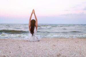 donna pratiche yoga e medita nel il loto posizione su il spiaggia foto