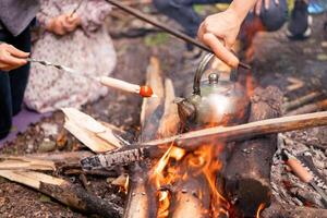 teiera salsiccia grigliato fuoco di bivacco su natura picnic falò preparazione cibo foto