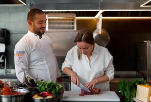 bello giovane africano capocuoco è cucinando insieme con il suo caucasico fidanzata nel il cucina utilizzando rosso vino come un ingrediente. foto