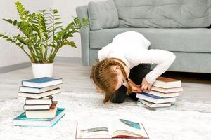 un' poco ragazza è guardare per il giusto libro nel un' pila foto