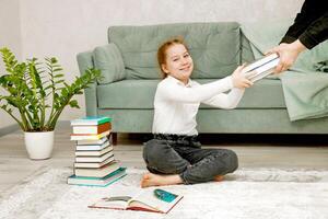 gioioso poco ragazza prende libri a partire dal il mani di un adulto foto