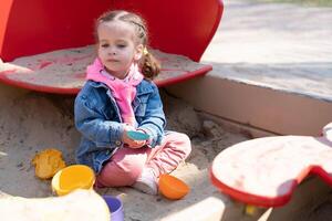 carino poco caucasico ragazza su il terreno di gioco, contento bambino con piacere la spesa tempo all'aperto, contento spensierato infanzia foto