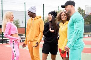 gruppo di giovane gli sport persone di diverso nazionalità nel abbigliamento sportivo comunicare a il stadio, a il Università. luminosa Abiti per gli sport. foto