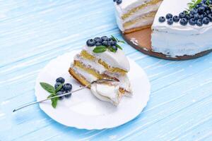 appetitoso torta di formaggio torta biscotto cuscino decorato bianca crema mirtilli e menta sta su di legno blu rustico tavolo foto