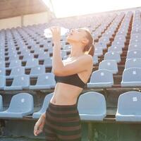 bellissimo caucasico ragazza atleta detiene nel sua mani un' acqua nel un' plastica bottiglia foto