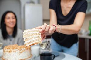 amici incontro con vino e torta nel il moderno stile cucina. donne Sorridi e scherzo foto