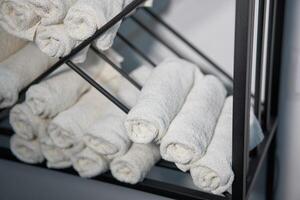 bianca pulito asciugamani lanciato su su un' rotolo siamo immagazzinato su scaffali nel un' bellezza salone nel un' barbiere spa. foto