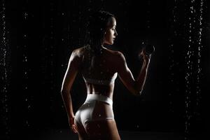 atletico donna pompaggio su muscoli con manubri foto