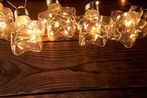 luminosa luminoso Natale ghirlande nel il forma di stelle menzogna su un' buio di legno sfondo. foto