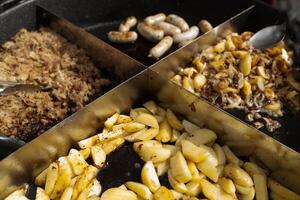 arrostito patate cucinato all'aperto nel grande metallo calderone pentola. strada veloce cibo foto