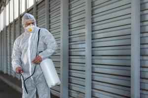 lavoratore indossare protettivo completo da uomo disinfezione Ingranaggio disinfettare superficie pubblico posto foto