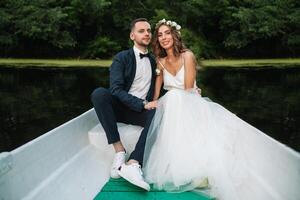 bellissimo coppia sposo e sposa vicino fiume barca. contro il sfondo di bellissimo natura e tramonto foto