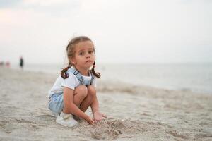 bambino giocando sabbia spiaggia poco ragazza giocare triste solo estate famiglia vacanza foto