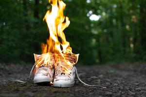 Usato bianca alto scarpe da ginnastica ardente su un' rurale strada quello corre nel il foresta. foto