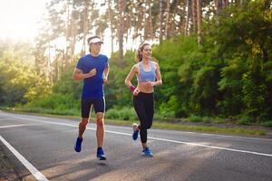 caucasico femmina gli sport donna e in forma uomo nel pieno corpo lunghezza in esecuzione pino foresta strada. salutare stile di vita concetto foto