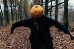 un' terribile creatura nel il autunno foresta nel il sera. contento Halloween. zucca testa. uomo con un' zucca su il suo testa e un' nero mantello foto