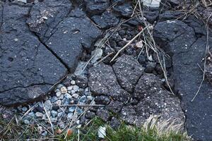 avvicinamento di veramente ruvido Cracked roccioso grunge asfalto sfondo struttura. foto