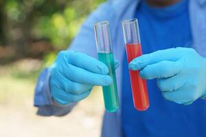 avvicinamento mani indossa blu guanti detiene test tubi quello contenere rosso e blu liquido sostanze dentro. scienza sperimentare. estratto colore. concetto, chimica lezione. laboratorio foto