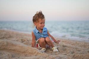 bambino giocando sabbia spiaggia poco ragazza giocare triste solo estate famiglia vacanza foto