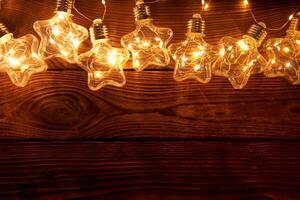 luminosa luminoso Natale ghirlande nel il forma di stelle menzogna su un' buio di legno sfondo. foto