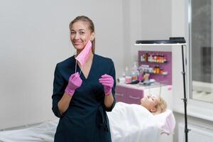 cosmetologia Consiglio dei ministri cliente bugie su divano. estetista sta nel rosa medico maschera e sorrisi. foto