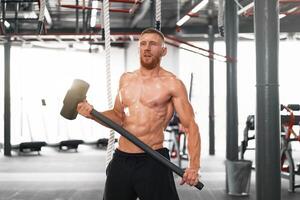 uomo Palestra martello colpire trattore ruota colpire enorme pneumatico atleta allegro uomo mezzo adulto bello sportivo bodybuilder sollevatore di pesi ideale corpo foto