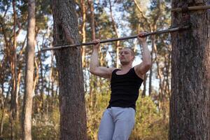 bello caucasico uomini pull-up all'aperto allenarsi attraversare formazione mattina pompaggio su braccio esercizio gli sport terra natura foresta foto