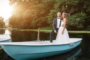 bellissimo coppia sposo e sposa vicino fiume barca. contro il sfondo di bellissimo natura e tramonto foto