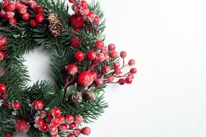 Natale decorativo ghirlanda di agrifoglio, edera, vischio, cedro e leyland foglia rametti con rosso frutti di bosco al di sopra di bianca sfondo. foto