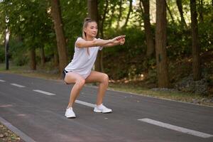 donna corridore allungamento gambe prima esercizio estate parco mattina foto