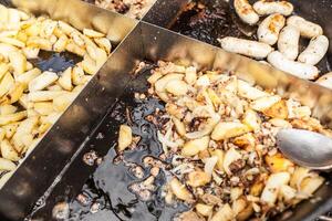 arrostito patate cucinato all'aperto nel grande metallo calderone pentola. strada veloce cibo foto