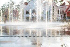 irriconoscibile contento bambini avere divertimento giocando nel città asciutto acqua Fontana su caldo estate giorno foto