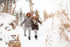 un' giovane coppia, un' uomo e un' donna siamo a piedi nel un' inverno innevato foresta. inverno tempo libero. viaggio insieme. amore volontà caldo nel qualunque brina foto