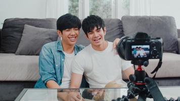 giovane coppia gay asiatica influencer coppia vlog a casa. gli uomini lgbtq coreani adolescenti si rilassano felici e si divertono usando il video del vlog della registrazione della fotocamera nei social media mentre si trovano sul divano nel soggiorno al concetto di casa. foto