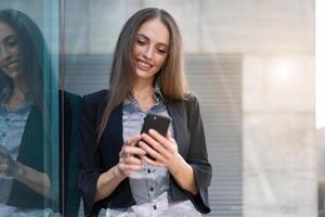 attività commerciale donna 35 anni vestito banda camicia e nero giacca con lungo capelli in piedi vicino ufficio edificio all'aperto uso smartphone foto