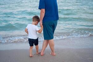 padre figlio la spesa tempo insieme mare vacanza giovane papà bambino poco ragazzo a piedi spiaggia foto