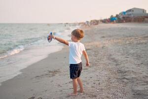 caucasico ragazzo in piedi spiaggia. infanzia estate. famiglia vacanza foto