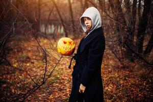 giovane donna nel un' grigio cappuccio Tenere il Halloween zucca foto