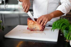 irriconoscibile giovane africano capocuoco in piedi nel professionale cucina nel ristorante preparazione un' pasto di carne e formaggio verdure. foto