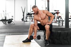 Palestra atleta bicipite esercizio manubrio muscolare uomo sedersi ruota Tenere sollevamento bilanciere. foto